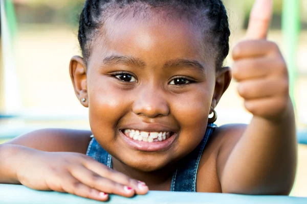 Foto facial de menina africana fazendo polegares ao ar livre . — Fotografia de Stock