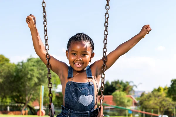 Criança africana feliz levantando os braços no balanço — Fotografia de Stock