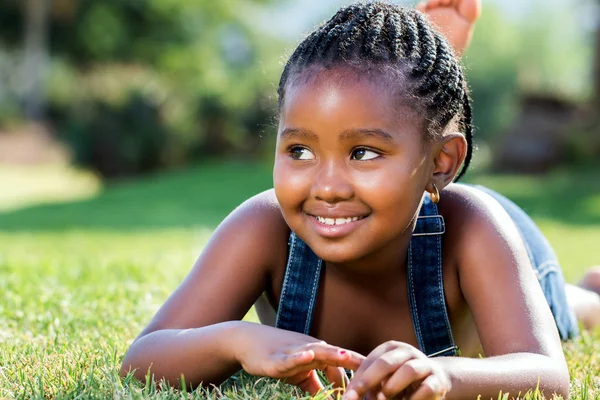 Schattig Afrikaanse meisje opleggen van groen gras — Stockfoto