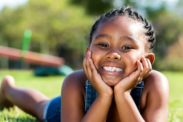 Jolie fille africaine couchée sur l'herbe verte — Photo