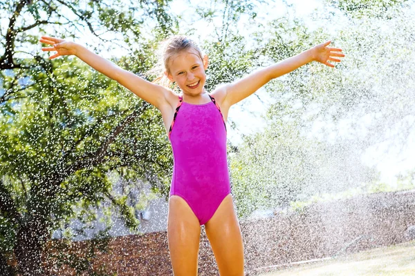 Niña gritando bajo el rociador de agua . —  Fotos de Stock