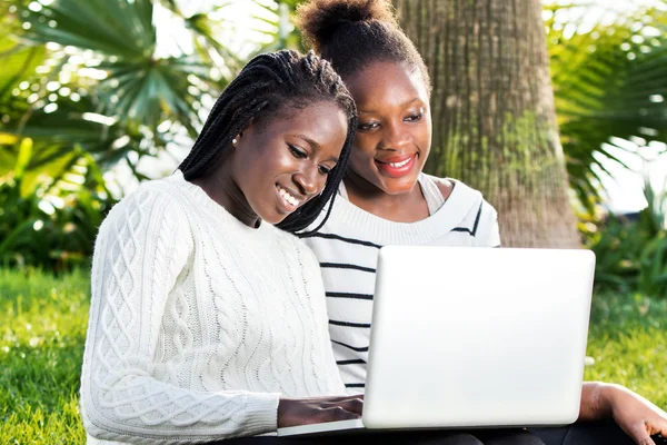 Afrikaanse tieners spelen op laptop in park. — Stockfoto