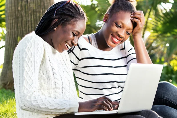 Afrikaanse meisjes plezier op laptop in park. — Stockfoto