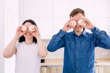 Genç evli çift mutfakta kahvaltı hazırlıyor gözlerini mantarla kapayıp gülüyorlar..