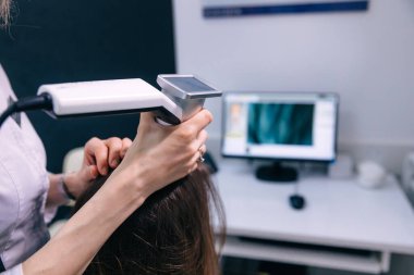 Doktor özel dermatoloji ekipman sistemi, saç dökülmesi ve trikoloji konsepti olan bir hastanın kafa derisini inceliyor.