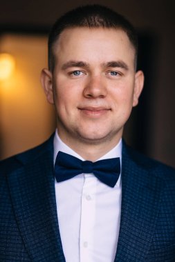 Beyaz gömlekli ve papyonlu zarif damat düğün gününde gülümsüyor..