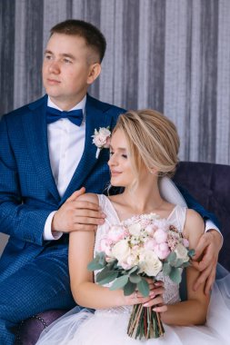 Düğün günü güzel, rahat bir evde bir çift bir koltukta oturur, bir kız buketi tutar..