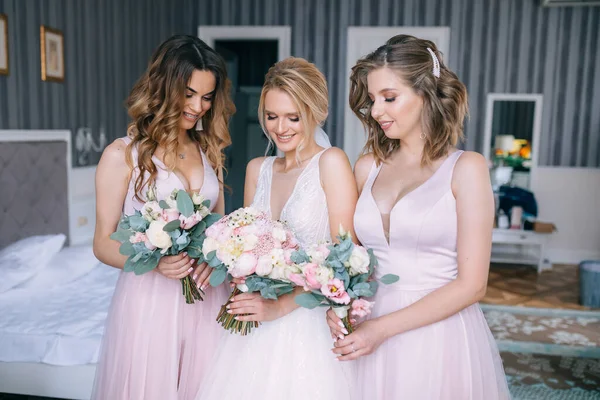 身着粉色婚纱的伴娘们簇拥着一个手持婚纱的漂亮新娘 — 图库照片