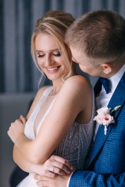 Beyaz elbiseli güzel bir gelin ve takım elbiseli bir damat kızı kucaklıyor ve öpüyor..