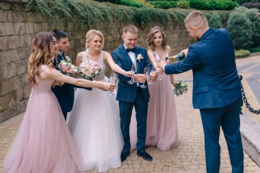 Damadın arkadaşı bir şişe şampanya açıyor ve yeni evliler düğünü kutluyor..