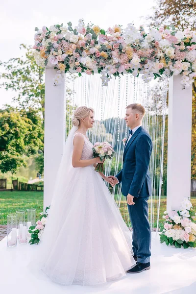 Mutlu Gelin Damat Kucaklaşır Birbirlerinin Gözlerinin Içine Bakar Çiçeklerle Süslenmiş — Stok fotoğraf