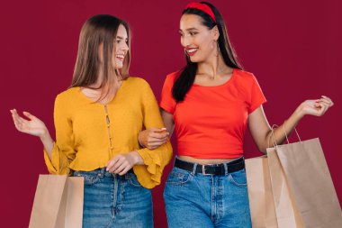 En iyi arkadaşlarla alışveriş günü. Alışveriş yaptıktan sonra elinde kesekağıdıyla bekleyen iki çekici genç kadın..