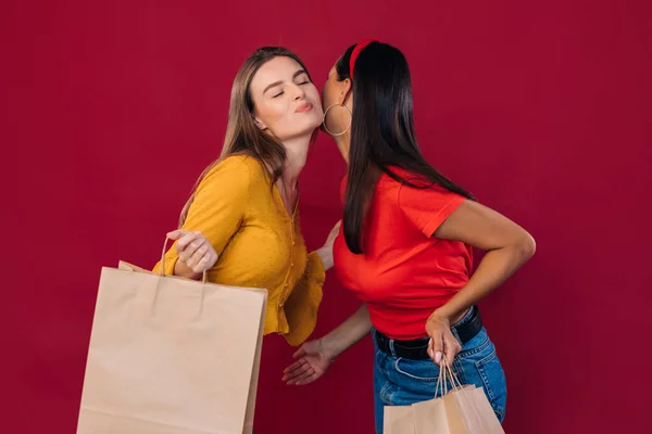 girls friends hold a package in their hands they say goodbye to air kisses, after shopping,.