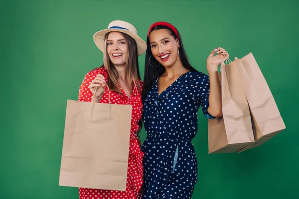 在演播室里 两个穿着绿色背景衣服的年轻女性朋友很开心 人的生活方式概念 购物后留个包 — 图库照片