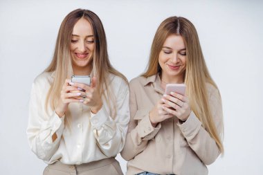 İki mutlu kadın arkadaş akıllı bir telefonla sosyal medyayı paylaşıyor ve oynuyorlar..