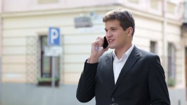 Yakışıklı iş adamı şehir caddesinde yürüyor, kahve içiyor ve cep telefonuyla konuşuyor..