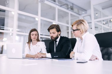 Ciddi bir erkek lider ve meslektaşları masada oturur ve hatalara işaret ederler..