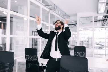 Genç çılgın yakışıklı iş adamı şirket lobisinde başarıları kutlamak için dans ediyor.