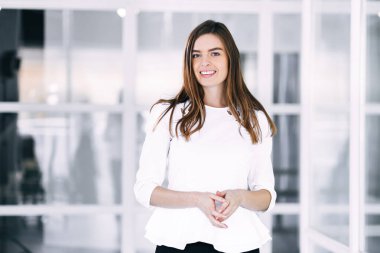 İş yerinde kollarını kavuşturmuş gülümseyen güzel bir iş kadını..