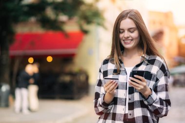 Çevrimiçi alışveriş ve mobil bankacılık için akıllı telefon kullanan kredi kartı tutan bir kız. Genç serbest çalışan maaşını alır, dengeyi kontrol eder. Kadın internetten yemek sipariş ediyor, kitap bileti.
