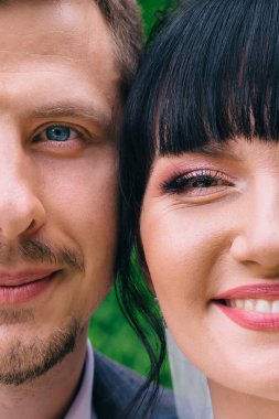 İki yüzün yarısı gülen gelin ve damada yakın. Yeni evlilerin düğün portresi..