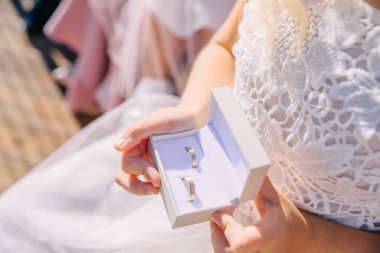 Elbisenin arka planında lüks bir alyans olan beyaz bir kutu tutan kadın. Yakın plan..