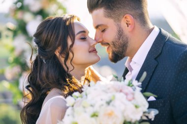 Açık havada kemerin yanında öpüşen mutlu, romantik bir çiftin portresi..