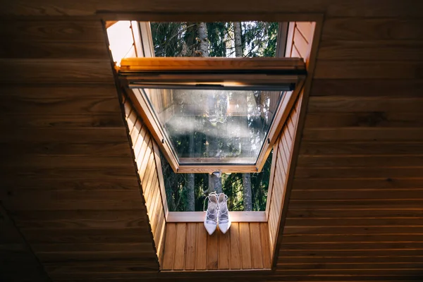 White wedding shoes in the window with a garden view in the background. Preparation, morning bride.