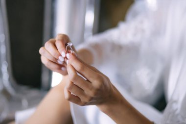 Gelin bir alyans tutuyor. Parmaklarını güzel bir manikürle kapat.