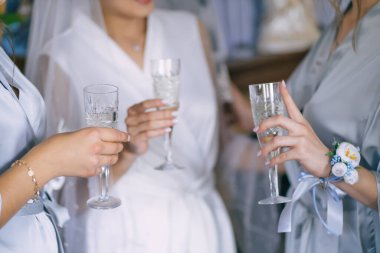 Gelin ve nedimeler ellerinde şampanya kadehleriyle ipek bornozlar içinde duruyorlar. .