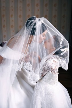 Lüks bir gelinlik içinde güzel bir gelin ve güzel bir kız sabah evde peçenin altında sarılıyor..