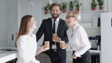 Ofiste dikilen bir grup işadamının görüntüsü. Başarılı bir alışverişe adanmış gayri resmi bir toplantı. İş ortakları eğleniyor. Gençler kağıt bardaktan lezzetli bir kahve içiyorlar..