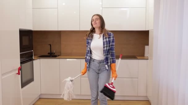 这个女孩在打扫时 戴着手套 用拖把跳舞唱歌 心情很好年轻女人打扫房子 — 图库视频影像