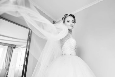 Açık beyaz elbiseli ve törenden önce sabahları duvak takan kibar, modern bir kız. Modaya uygun bir gelin imajı.