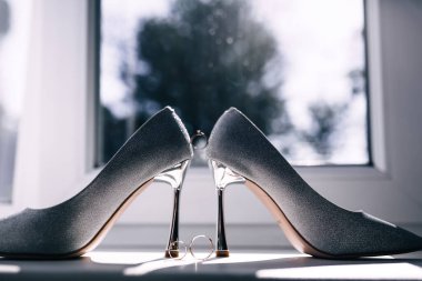 Güzel kadın ayakkabıları yüksek topuklularla pencere eşiğinde duruyor.