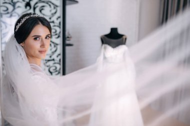 Gelinin sabahı. Sanatsal düğün. Beyaz cüppeli, zarif bir şekilde peçesini sallayan genç ve güzel bir kız..