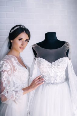 Gelini yaklaşan düğüne hazırlıyorum. Kız gösterişli beyaz elbisesini gösteriyor.