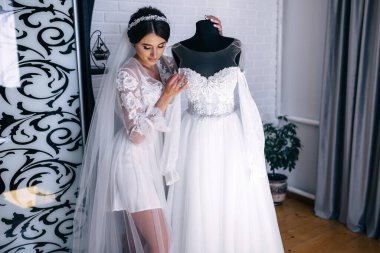 Gelinin sabahı. Muhteşem gelin. Elbisenin yanında beyaz bornozlu güzel bir kadın. Doğal güzellik ve profesyonel makyaj..