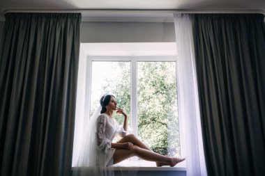 Kır evinde, pencerenin yanında sabahlık giymiş güzel, genç bir gelin. Gelinin düğün günü sabahı. Mutlu kadın damadı ile bir toplantı bekliyor. Mutlu ve lüks evlilik kavramı..