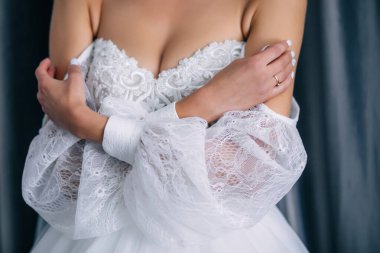 Gelinin düğün sabahı. Altın yüzükle yakın plan çek. Nazik manikür. Elbisenin beyaz kolları..