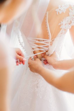 Nedime gelini düğün gününe hazırlıyor düğmelerini ilikleyip arkadan bağlamasına yardım ederek. Kadınların sabah toplantısı..