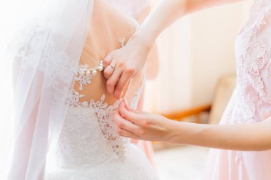 Arkadan bak. Nedime düğün günü için bir kadın hazırlar, törenden önce gelinliği düzeltmeye yardım eder..