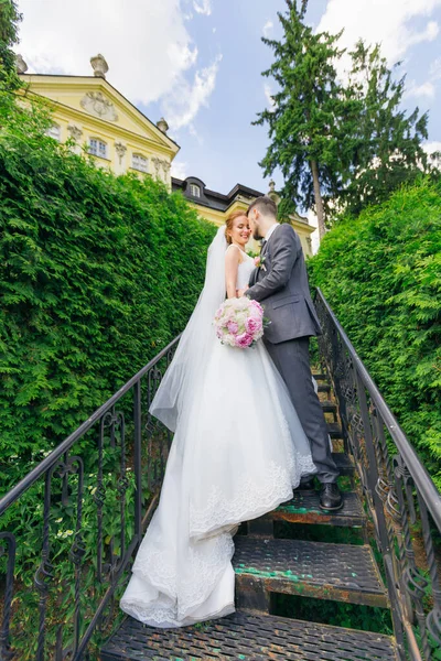 Novomanželé Stojí Schodech Starého Paláce Obklopeni Zelenými Listy Obejmutí Nevěsty — Stock fotografie