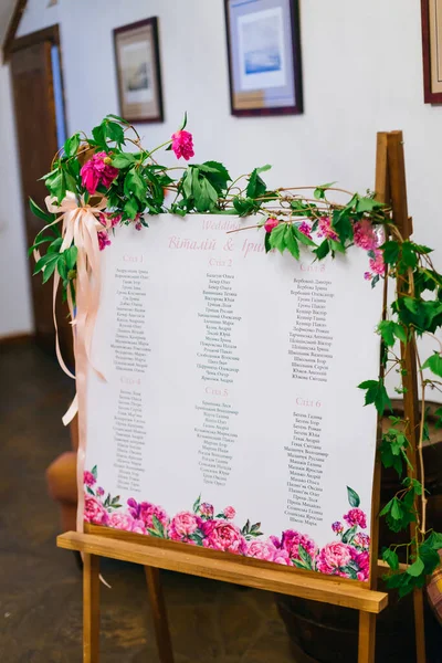 Beautiful elegant and stylish wedding guest list with floral decor on a wooden frame