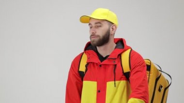Teslimat hizmeti konsepti. Üniformalı ve termal çantalı kendinden emin gülümseyen kuryenin portresi çapraz kollarla poz veriyor ve beyaz arka planda izole edilmiş kameraya bakıyor..
