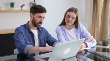 Genç erkek akıl hocası stajyere çevrimiçi bilgisayar projesinde yardım ediyor. Öğrenciler dizüstü bilgisayarla konuşuyor, birlikte ders anlatıyorlar..