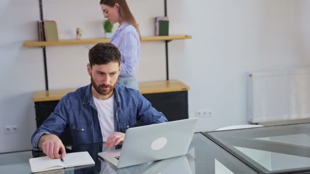 Hombre Serio Sienta Mesa Trabajando Con Casa Una Joven Camina — Vídeos de Stock