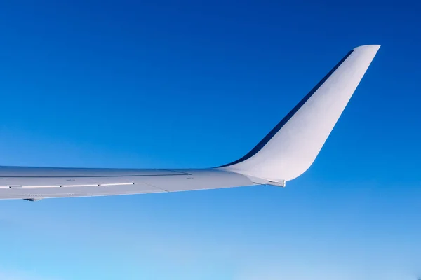 Airplane wing flying above the clouds. People look at the sky from the window of the plane, using air transport to travel.