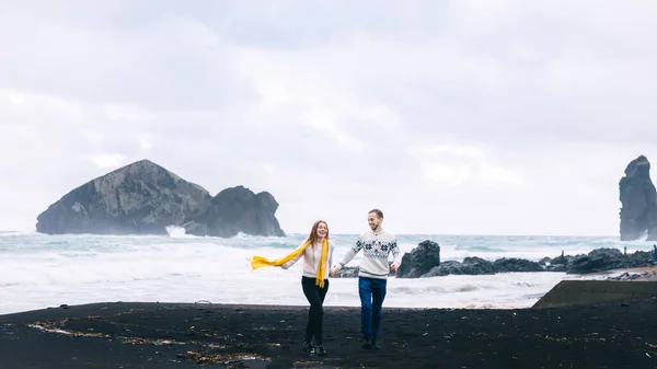 黒い砂 波が飛び散る嵐の海 そしてアイスランドのビーチで楽しむために走るカップル — ストック写真