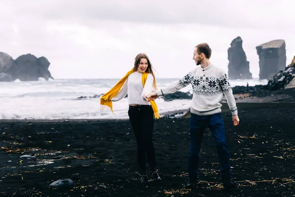 黒砂のビーチに南海岸を歩くアイスランドの観光客のカップル 幸せな女性と男が観光名所を訪れる — ストック写真